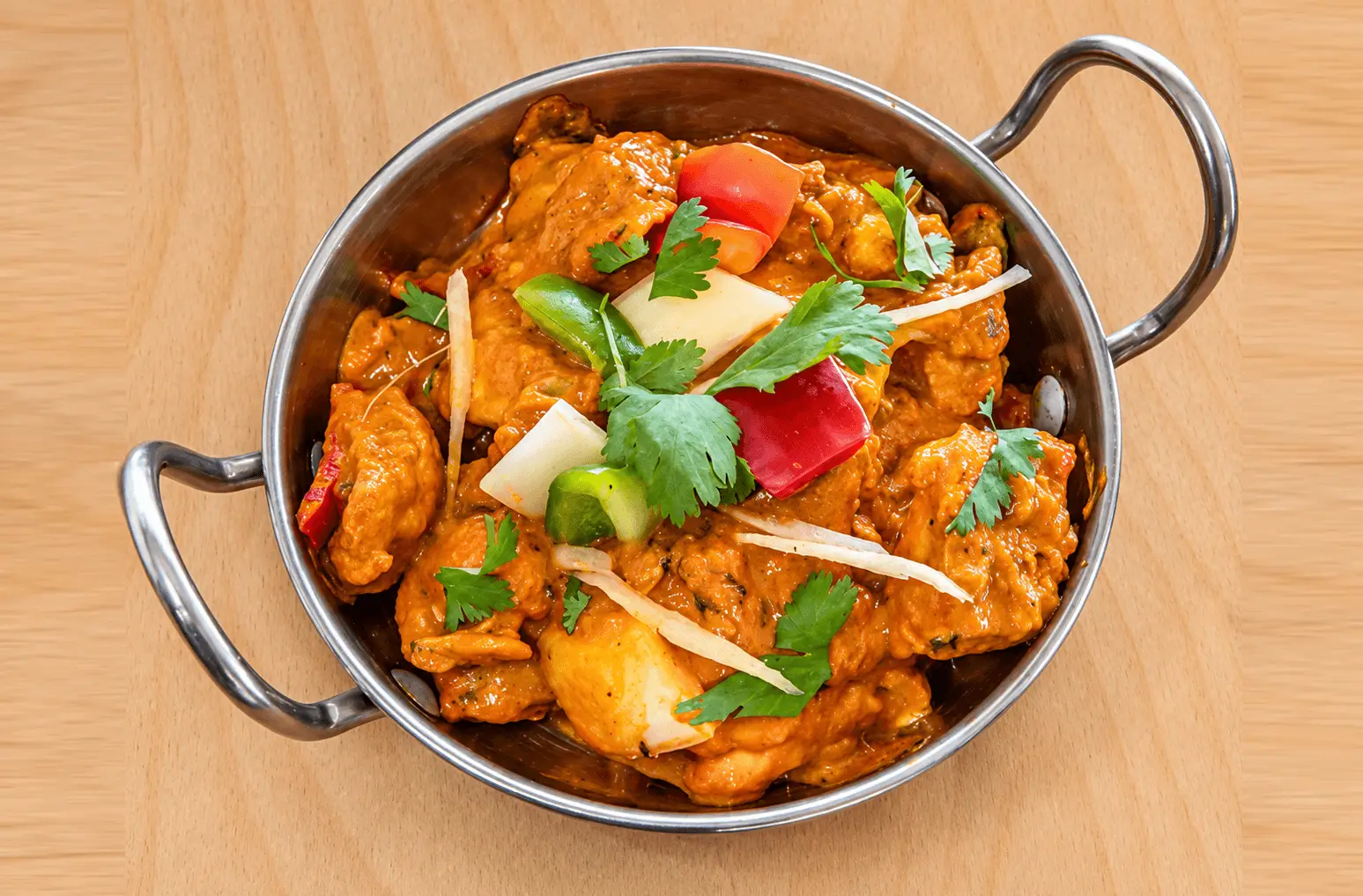 Curry served in a metal bowl with fresh garnish